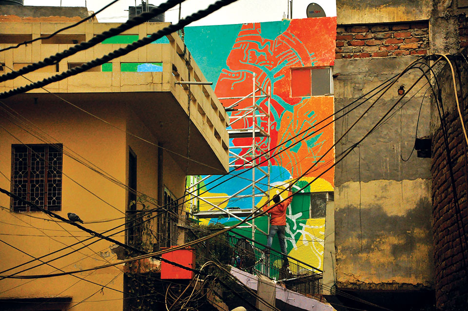 An artist adds color to a building in a Delhi alleyway. Photo by Vikram Kapur.