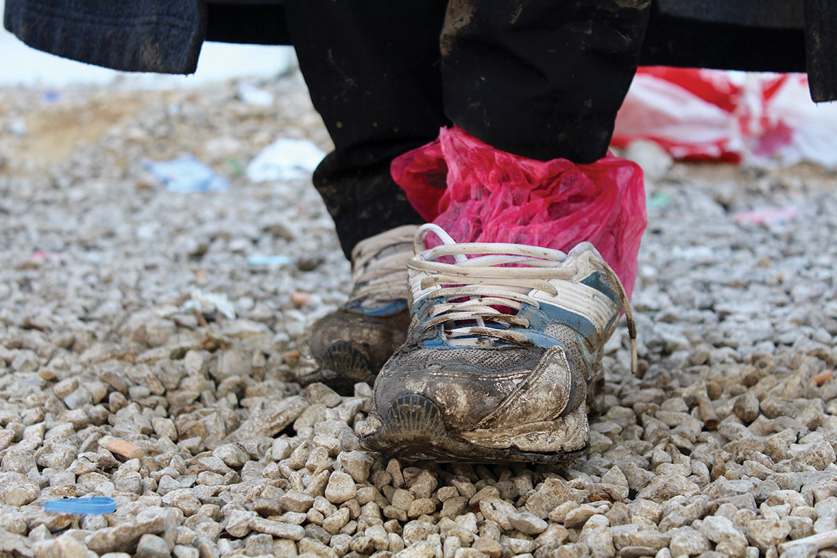 A refugee’s shoes are worn, wet, and muddy after a long journey. These shoes are owned by Ali, a Yazidi refugee who traveled from Iraq to Preševo, Serbia, to avoid persecution. Photo: Meabh Smith / Trócaire