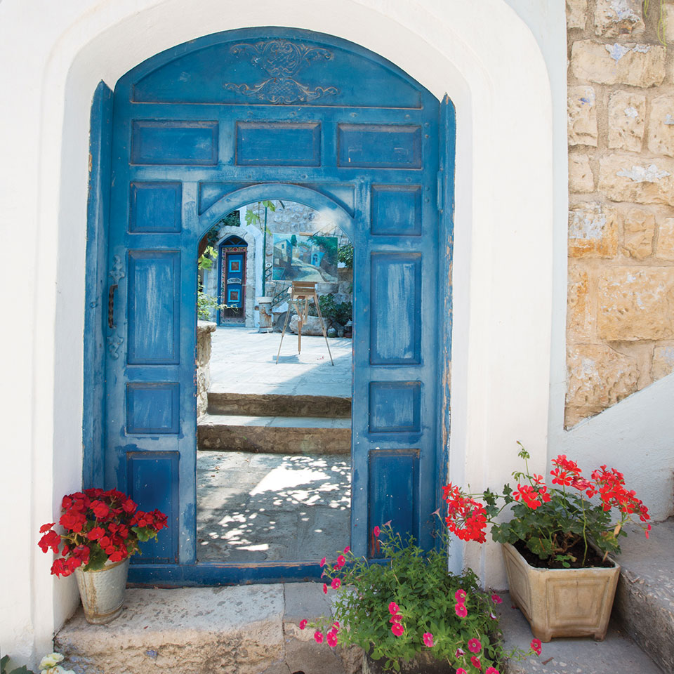 A blue door open before the viewer, revealing a courtyard within, in the city of Safed, Israel