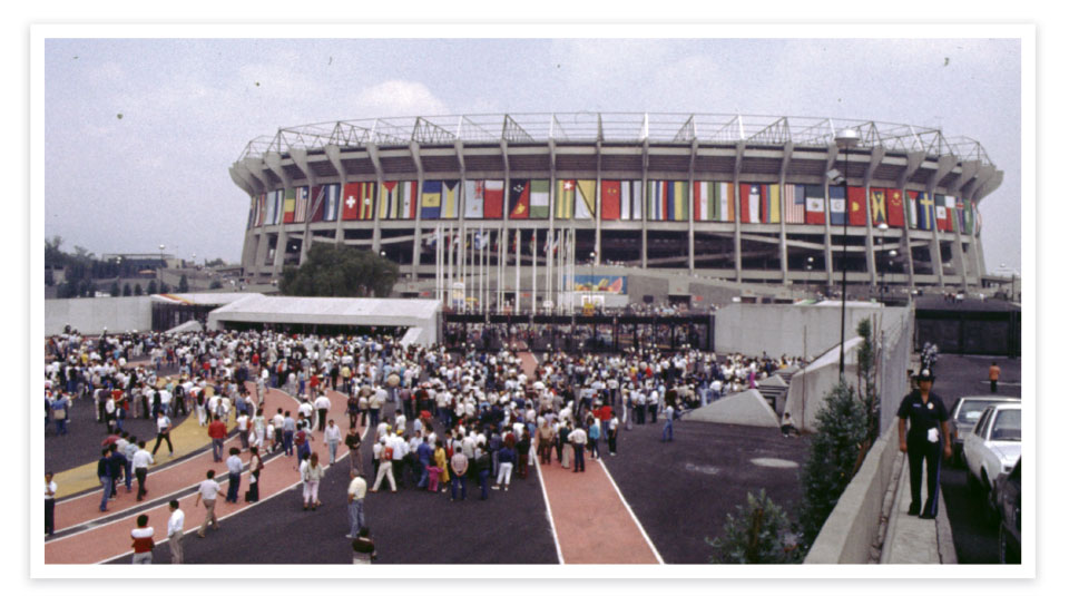 A crowd throngs into a stadium lined with flags from around the world