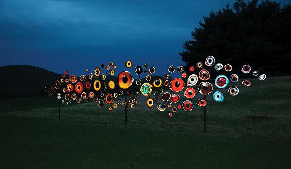 Many round objects, painted like bird's eye are mounted to poles and illuminated at night