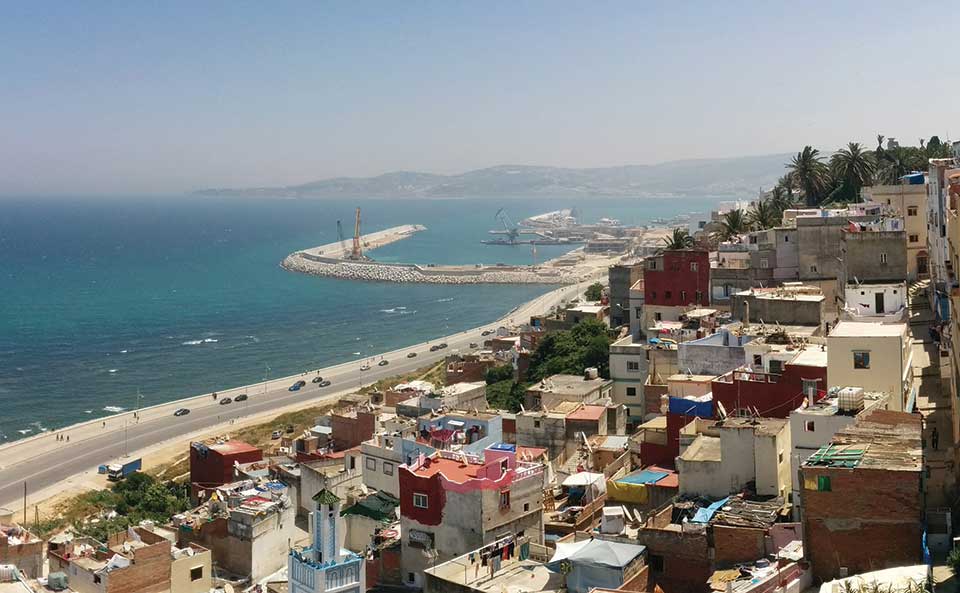A highway stretches along the sea as Tangiers rises up on the hillside bordering