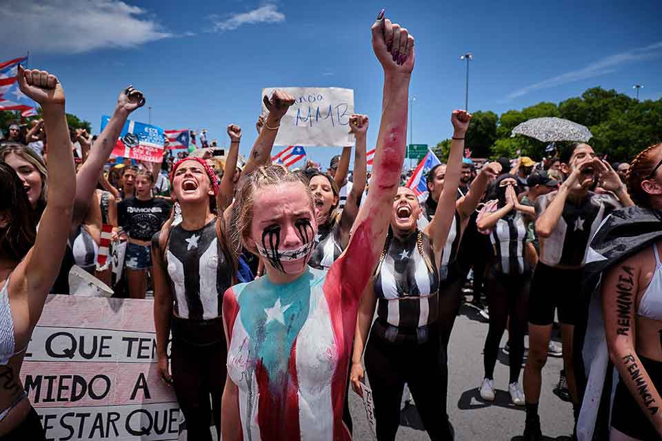 Women, arms raised in defiance, gather in protest