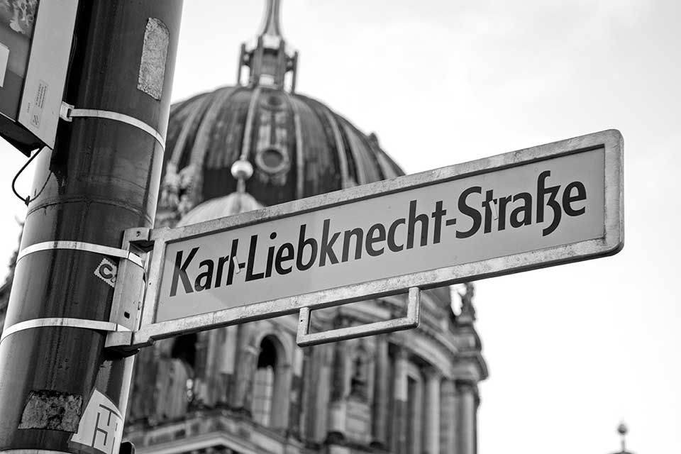A black and white photograph of a street sign that reads Karl Liebknecht Straße