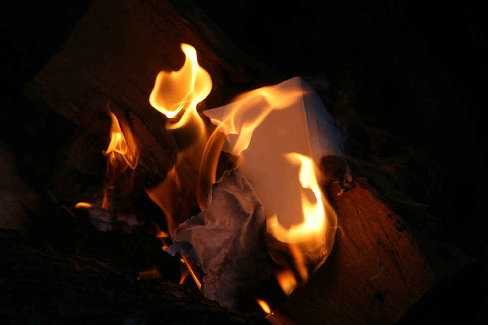 A photograph of paper burning up in a fire at night