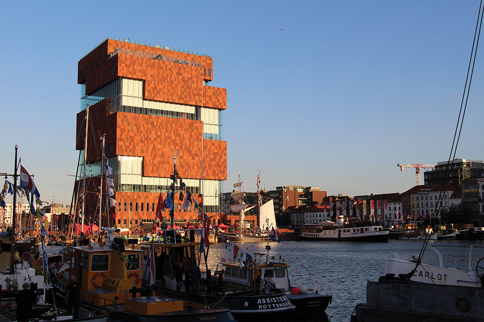 A blocky, multi-story building rises out of a river in Antwerp