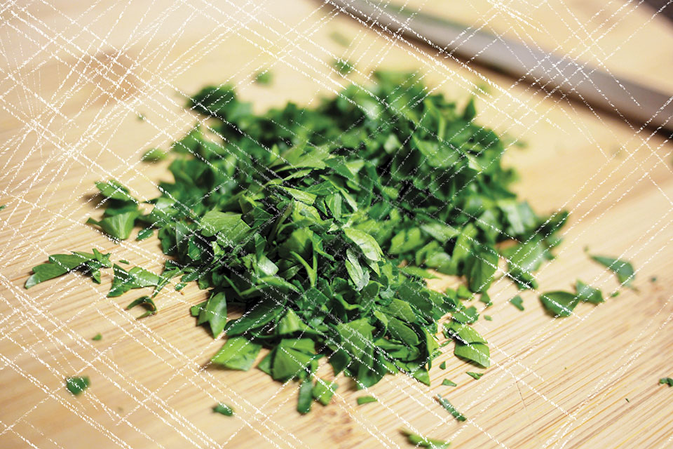 A pile of freshly chopped parsley on a knife-scarred cutting board
