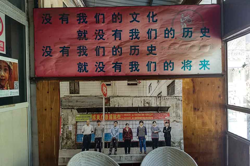 A photograph of several people standing in a row is mounted on a wall, beneath a banner adorned with Chinese characters