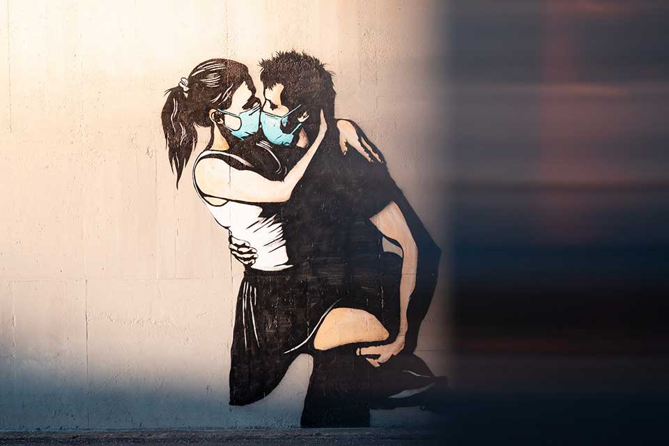 An illustration of a man and woman embracing. Both are wearing surgical masks