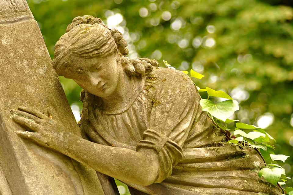 A photograph of a statue of a female figure clinging to a wall