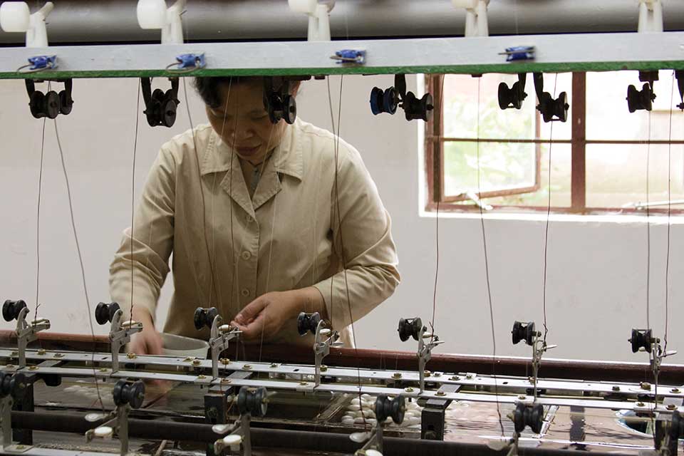A woman stands on the production line of an industrial garment factory
