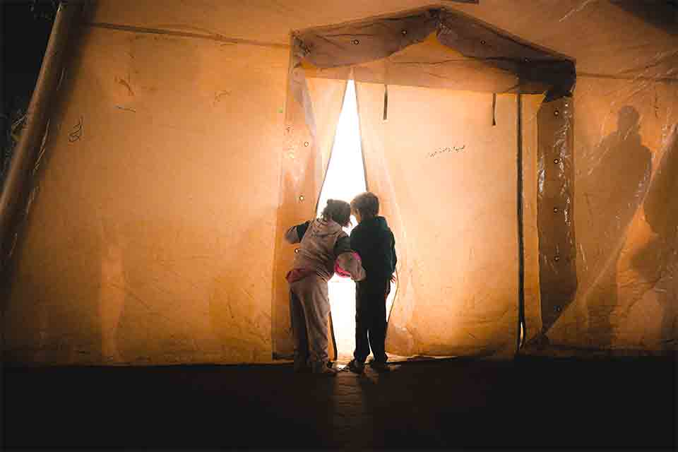 Two children peering out of a tent