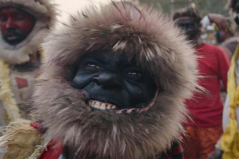 A tribal person in a fur-rimmed mask that accentuates the relationship between humans and monkeys