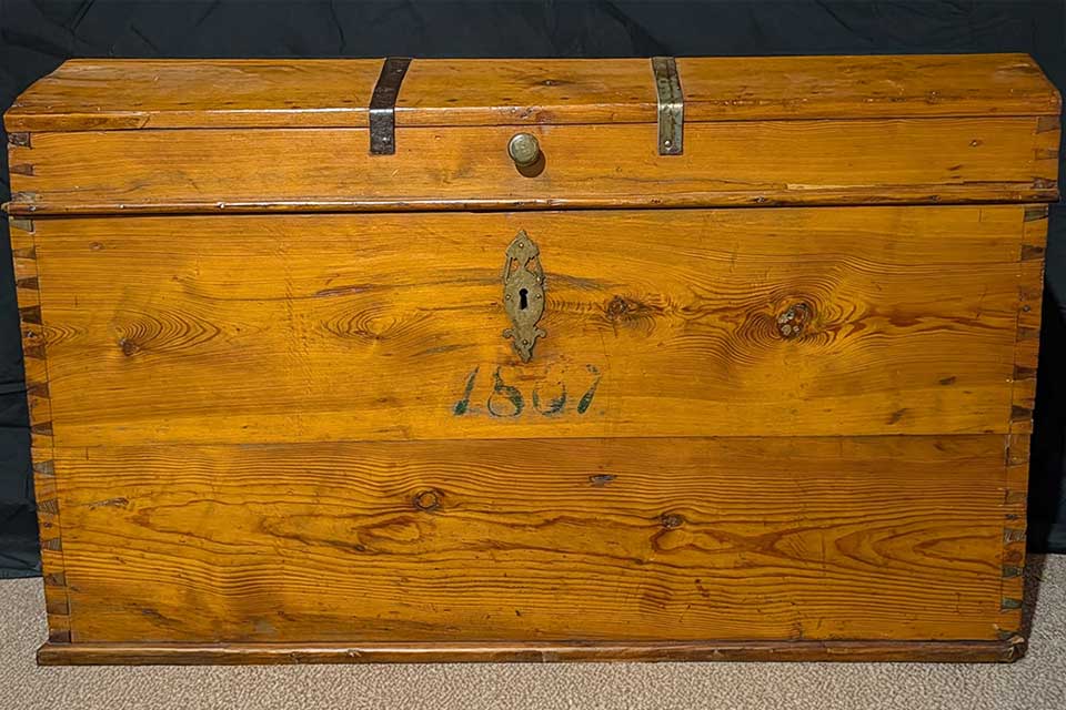 A wood steamer trunk. The numbers '1867' are stamped on the face