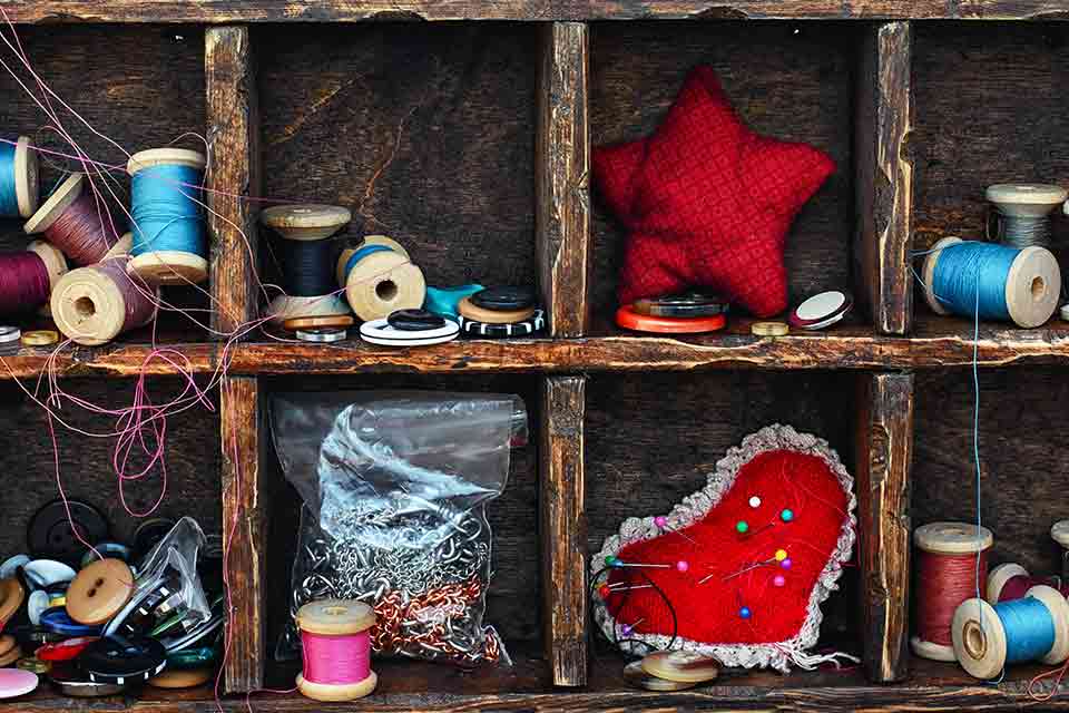 A sewing box on its side so that the bobbins and other sewing implements are visible