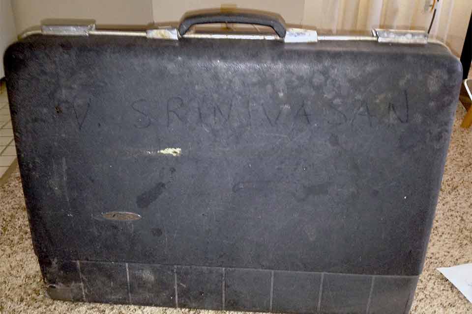 A worn older briefcase with the name V. Srinivasan written on it