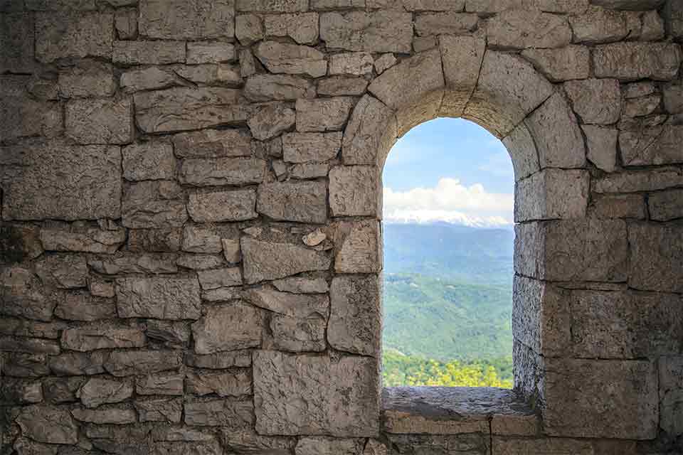 A doorway in a stone wall, looking out on to a field