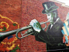 A photograph of a mural featuring a black man in a top hat playing trumpet