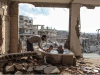 A man bathes two children in the rubble of a bombed-out apartment