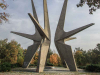 A photograph of an outdoor monument featuring three spiky geometric figures rising up out of the ground.