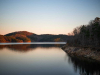 A placid lake at sunset with grassy land jutting out into it.