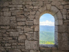 A doorway in a stone wall, looking out on to a field