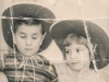 An old black and white photograph of a young boy and girl, both wearing cowboy hats, sitting next to one another