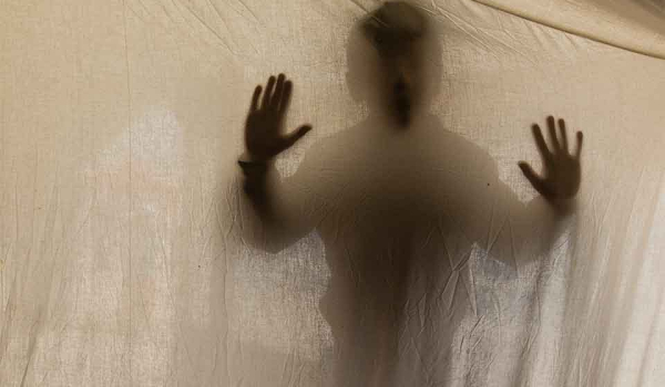 A shadowy figure presses into a translucent cloth