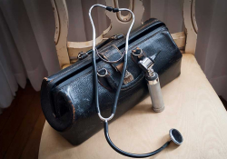 A medical bag with a stethoscope and an otolaryngioscope visible