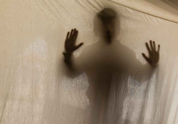 A shadowy figure presses into a translucent cloth