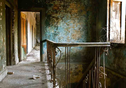 The landing of a two-story house. The house looks both dated and neglected and feels empty.