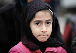A young girl, veiled in black, looks at the viewer glumly with a single tear running down her face