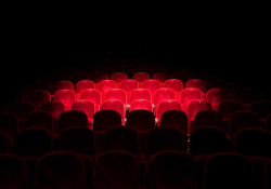 A row of theater seats, all but swallowed up by the darkness save for a spotlight on the inner circle