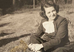 A sepia-toned photograph of a young woman sitting on a grass lawn.