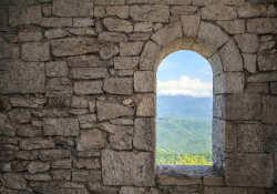 A doorway in a stone wall, looking out on to a field