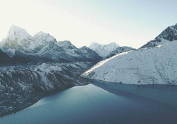 A landscape shot of snow-covered glaciers skirted by an apron of lakes