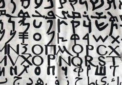 A photograph of the alphabet, each line in a different script, painted on a loose, white cloth