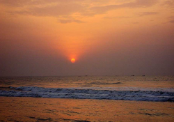 A red sun rises over the surf at dawn