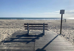 A photograph of an empty bench facing the ocean