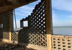 A photograph from inside a crumbling building that looks out toward the sea