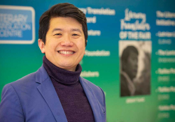 Jeremy Tiang posing in front of materials at the London Book Fair