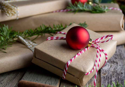 A photograph of books wrapped as gifts with a red ornament laying atop the one in the center