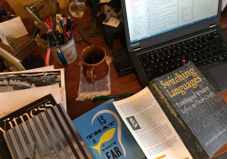 A top down photograph of a desk cluttered with books and a computer monitor nearby