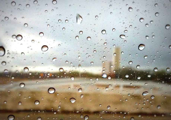 A photograph of a rural landscape, blurred by rain drops