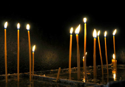 Thin, tapered, and lit candles arising from water