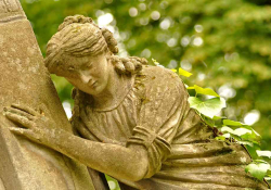 A photograph of a statue of a female figure clinging to a wall