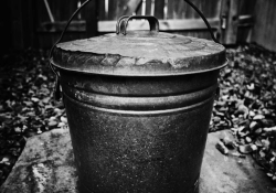 A black and white photograph of a black metal pail